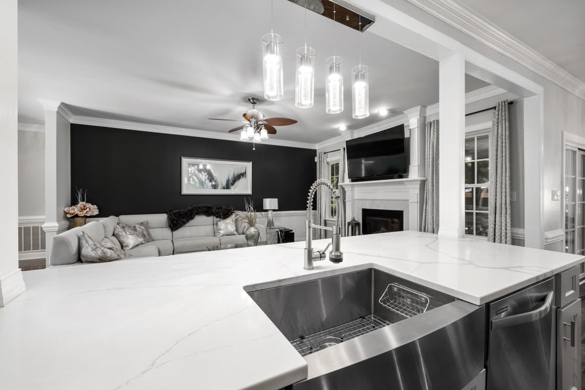 Cocina abierta al salón con isla, iluminación colgante y suelo de madera