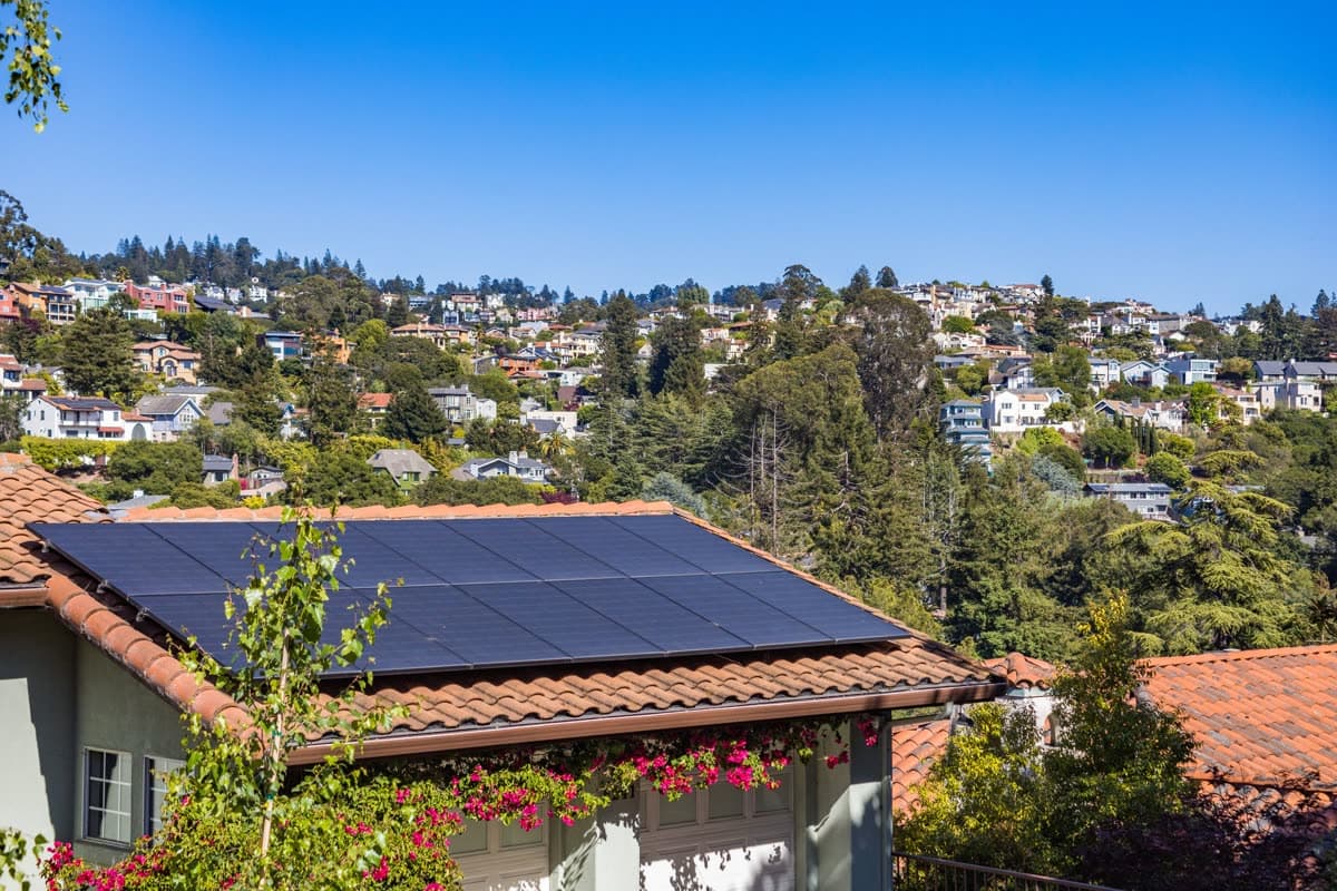 Paneles solares sobre el tejado de una vivienda en una zona residencial soleada